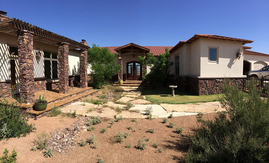 A custom home with a stone courtyard and outdoor living space in West Texas